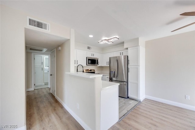 5217 Caspian Springs Dr Unit 101, Las Vegas, NV 89120 - kitchen with stainless steel appliances, light countertops, white cabinets, light wood finished floors, and recessed lighting