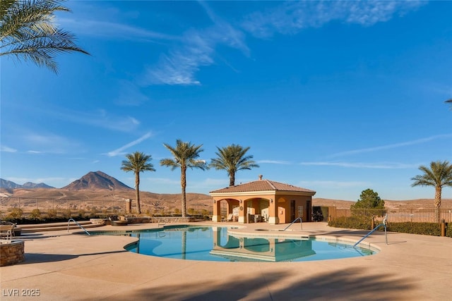 community pool with a mountain view, a patio area, and fence