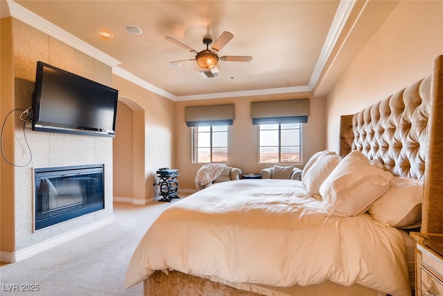 carpeted bedroom featuring ornamental molding, a fireplace, arched walkways, baseboards, and ceiling fan