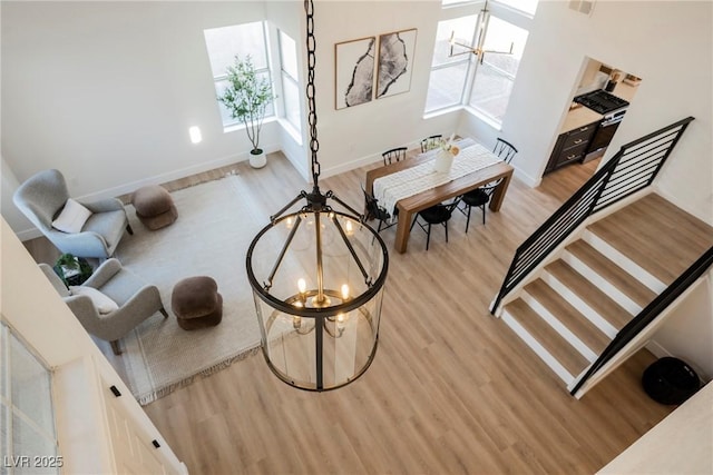 living area with a chandelier, light wood finished floors, and baseboards