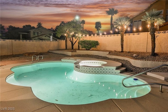 pool at dusk featuring a fenced backyard and a pool with connected hot tub