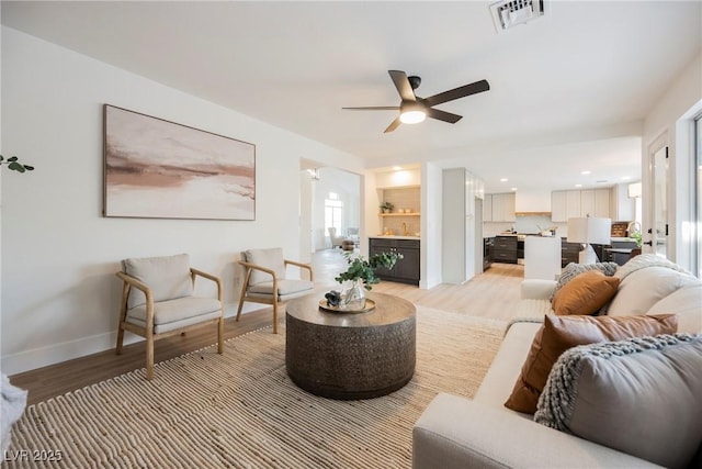 living room featuring light wood-type flooring, a ceiling fan, and baseboards