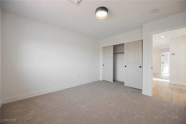 unfurnished bedroom with light carpet, a closet, and baseboards