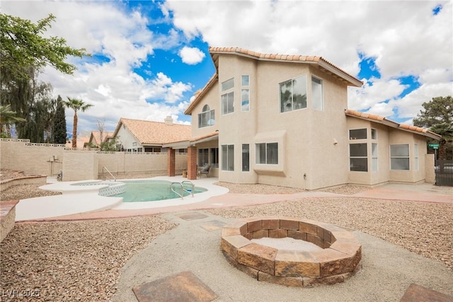 rear view of property with a fenced backyard, a patio area, a fire pit, and a tile roof