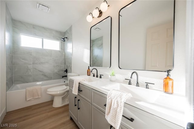 bathroom with toilet, wood finished floors, shower / washtub combination, and double vanity