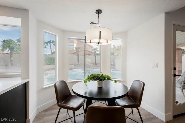 dining area with baseboards, healthy amount of natural light, and light wood-style flooring
