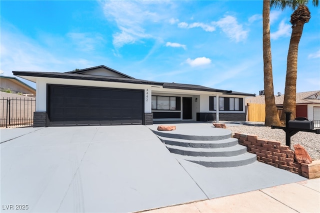 ranch-style home with an attached garage, concrete driveway, and fence