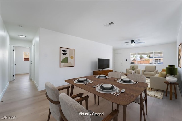 dining area with light wood finished floors, a ceiling fan, and baseboards