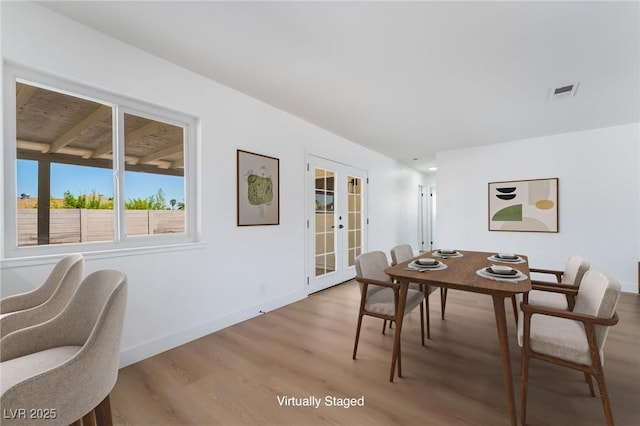 dining area featuring french doors, light wood-type flooring, and baseboards