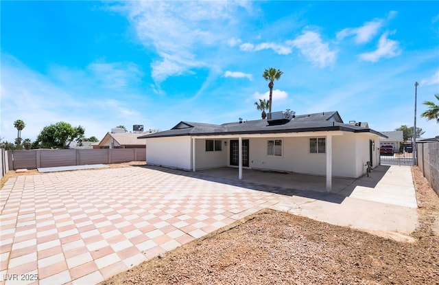 rear view of house featuring a fenced backyard, stucco siding, and a patio area