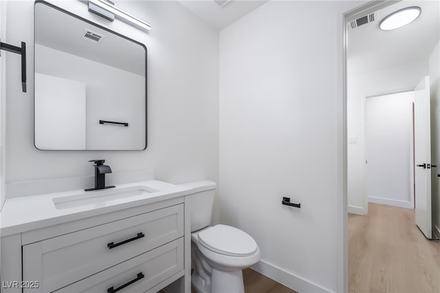 bathroom with wood finished floors, vanity, toilet, and baseboards
