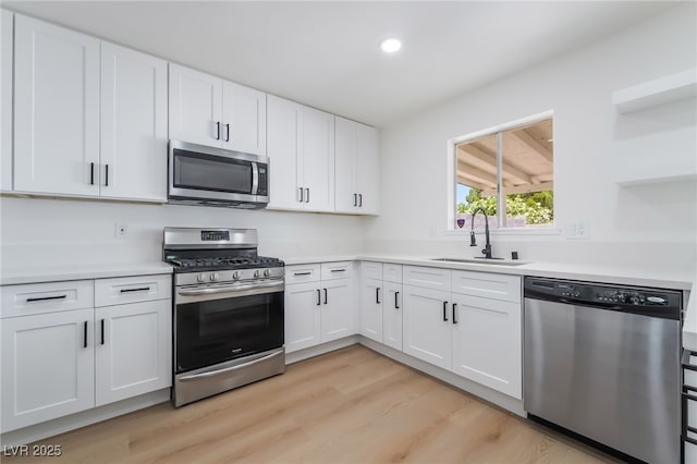 kitchen with appliances with stainless steel finishes, a sink, light wood-style floors, light countertops, and recessed lighting