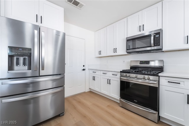 kitchen featuring appliances with stainless steel finishes, light wood-type flooring, light countertops, and white cabinetry