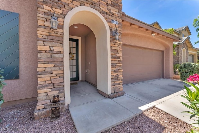 10353 Settlers Run Ave, Las Vegas, NV 89166 - view of exterior entry featuring stone siding, stucco siding, an attached garage, and driveway