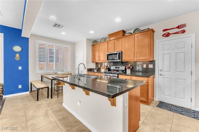 10353 Settlers Run Ave, Las Vegas, NV 89166 - kitchen with appliances with stainless steel finishes, a sink, an island with sink, backsplash, and light tile patterned floors