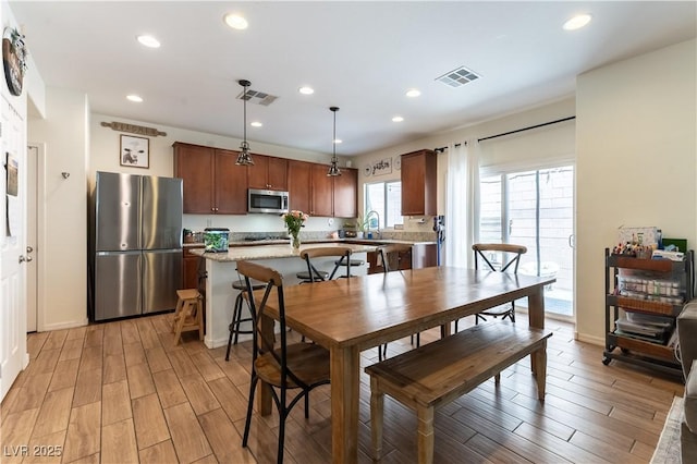 dining space with light wood-style flooring, recessed lighting, and baseboards