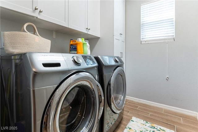 laundry area featuring separate washer and dryer, cabinet space, baseboards, and light wood finished floors