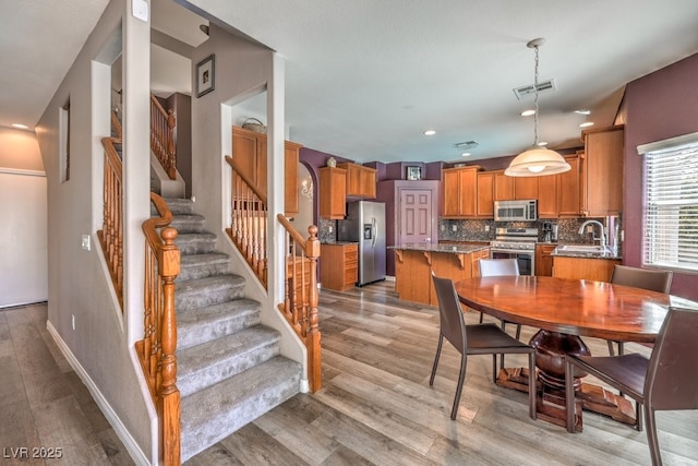 dining area with light wood-type flooring, stairs, baseboards, and recessed lighting