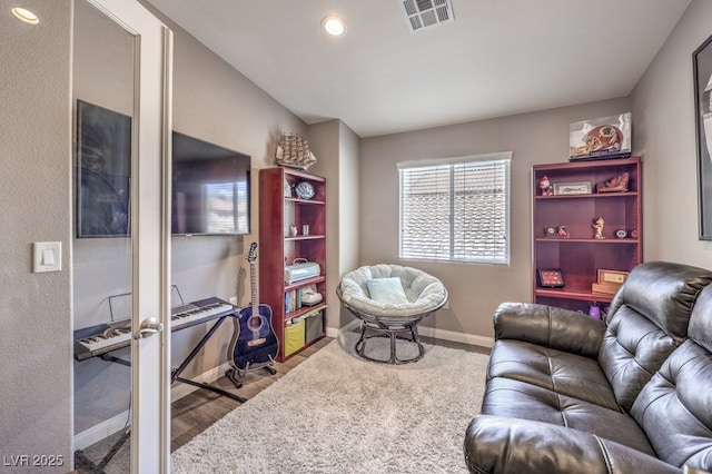 living area with baseboards, wood finished floors, and recessed lighting