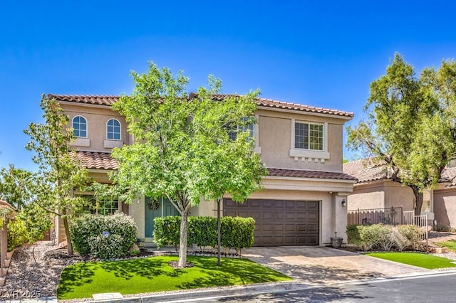 mediterranean / spanish home featuring an attached garage, a tile roof, stucco siding, and driveway