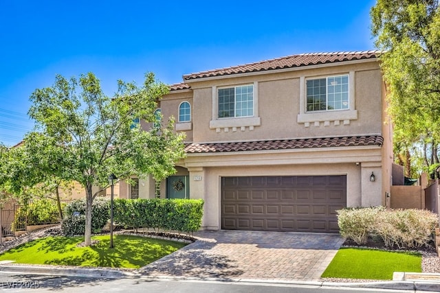 view of front of home featuring a tiled roof, an attached garage, decorative driveway, and stucco siding