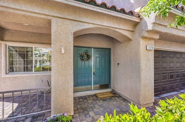 doorway to property with stucco siding and a garage