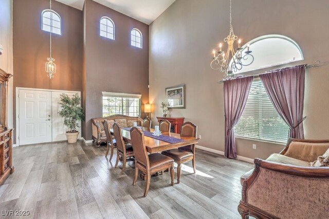 dining room featuring a chandelier, a high ceiling, wood finished floors, and baseboards