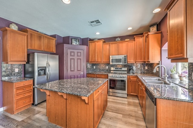 kitchen with stainless steel appliances, a sink, a kitchen island, light wood-type flooring, and recessed lighting