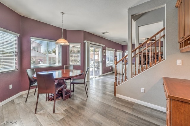 dining area with baseboards, stairs, light wood-type flooring, and plenty of natural light