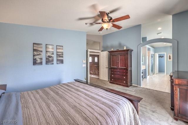 bedroom with arched walkways, light colored carpet, vaulted ceiling, and a ceiling fan