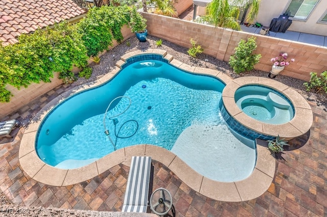 view of pool with a fenced backyard and a pool with connected hot tub