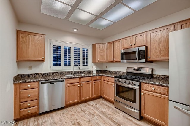 8613 Linderwood Dr, Las Vegas, NV 89134 - kitchen with appliances with stainless steel finishes, a sink, light wood-style floors, dark stone countertops, and recessed lighting