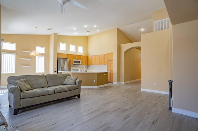 9710 Geiger Peak Ct, Las Vegas, NV 89148 - living area featuring light wood-type flooring, arched walkways, baseboards, a ceiling fan, and high vaulted ceiling