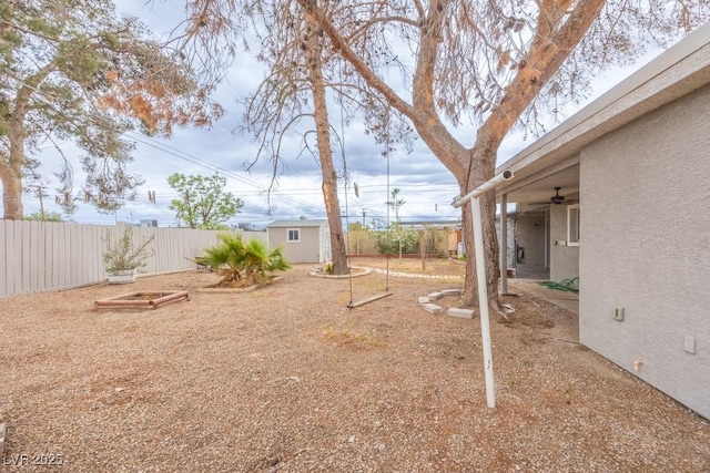 fenced backyard featuring a storage shed, an outbuilding, and ceiling fan