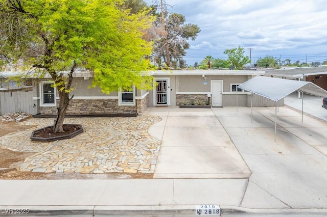 view of front facade with stone siding, stucco siding, and concrete driveway