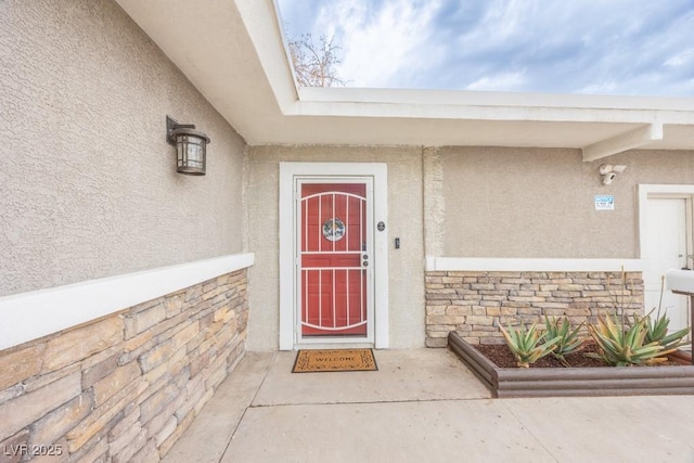 view of exterior entry with stucco siding and stone siding
