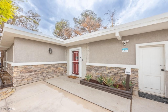 doorway to property featuring stone siding and stucco siding
