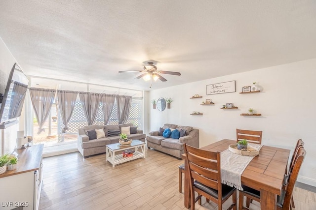 living room featuring a ceiling fan, a textured ceiling, and light wood-style flooring