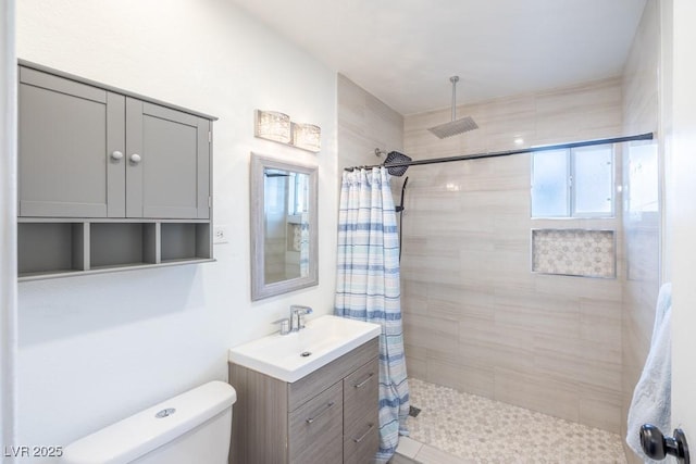 bathroom with a tile shower, toilet, and vanity