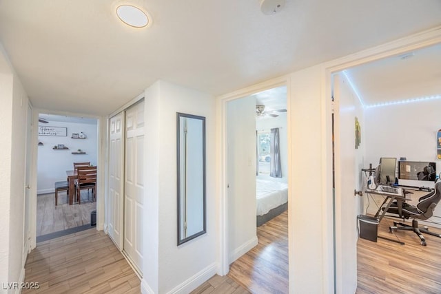 hallway featuring light wood-style flooring, an office area, and baseboards