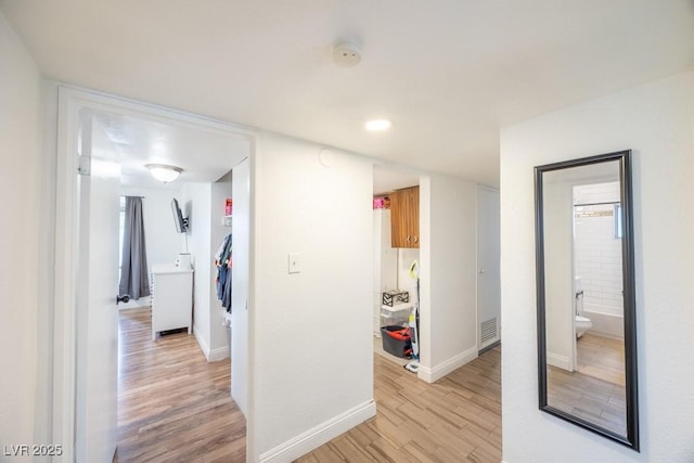 hallway with light wood-type flooring and baseboards