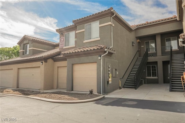 6868 Sky Pointe Dr Unit 1112, Las Vegas, NV 89131 - view of front of house with stairway, stucco siding, a tiled roof, and an attached garage
