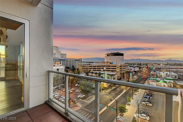 balcony at dusk featuring a city view and a mountain view