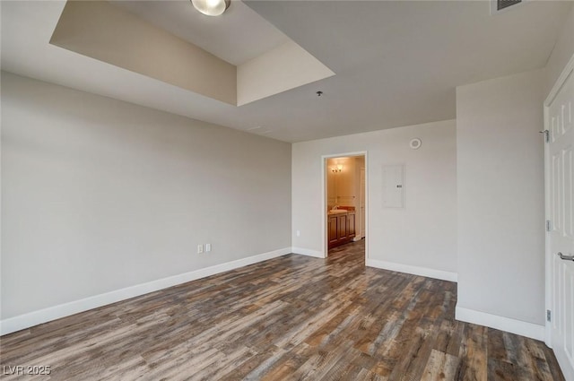 spare room with dark wood-style floors, baseboards, and electric panel