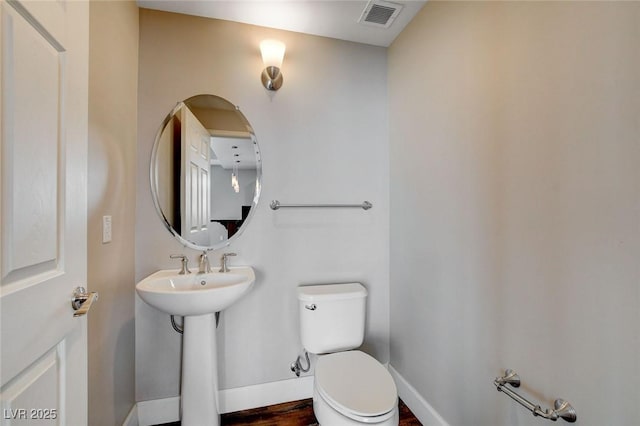 half bath featuring toilet, baseboards, wood finished floors, and a sink