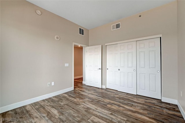 unfurnished bedroom with wood finished floors, baseboards, and a closet