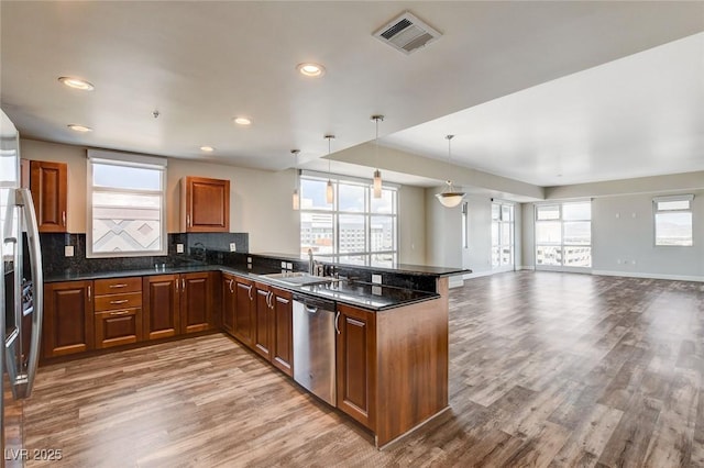 kitchen featuring stainless steel appliances, a sink, light wood-style flooring, open floor plan, and healthy amount of natural light