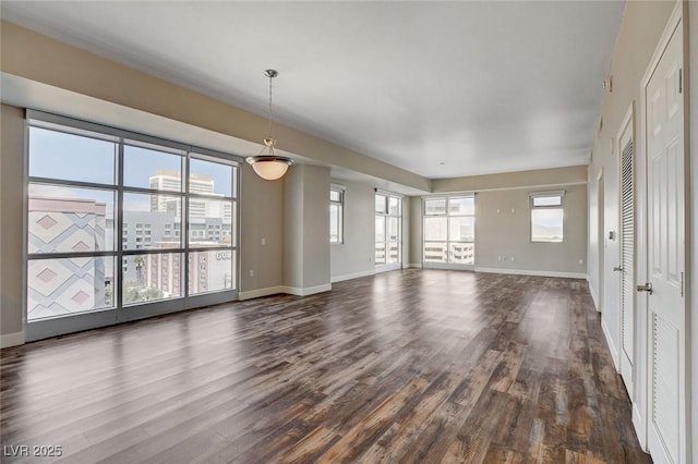 unfurnished living room with dark wood-style flooring and baseboards