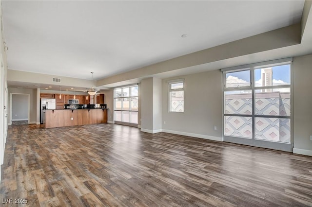 unfurnished living room with dark wood-type flooring and baseboards
