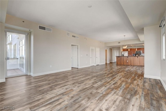 unfurnished living room featuring wood finished floors and baseboards